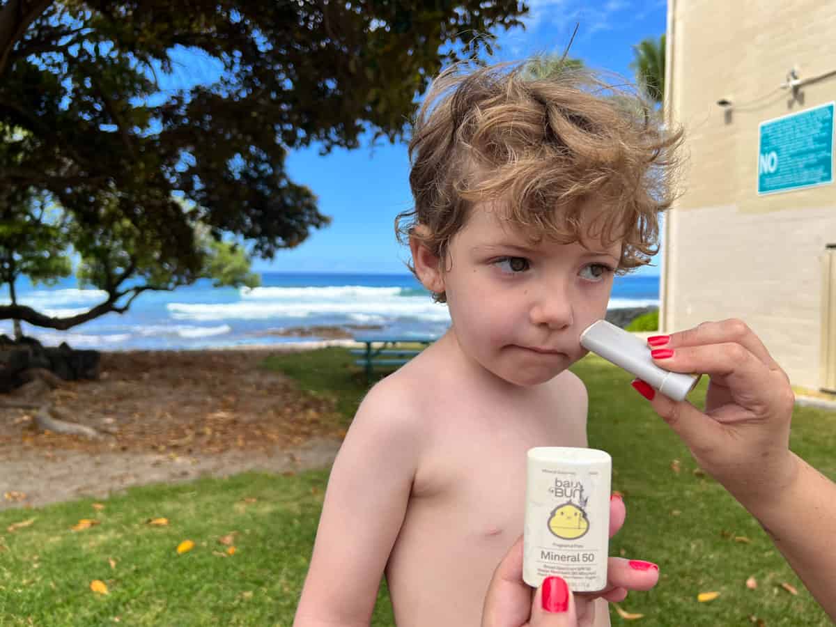 Applying a reef safe face stick sunscreen at the beach